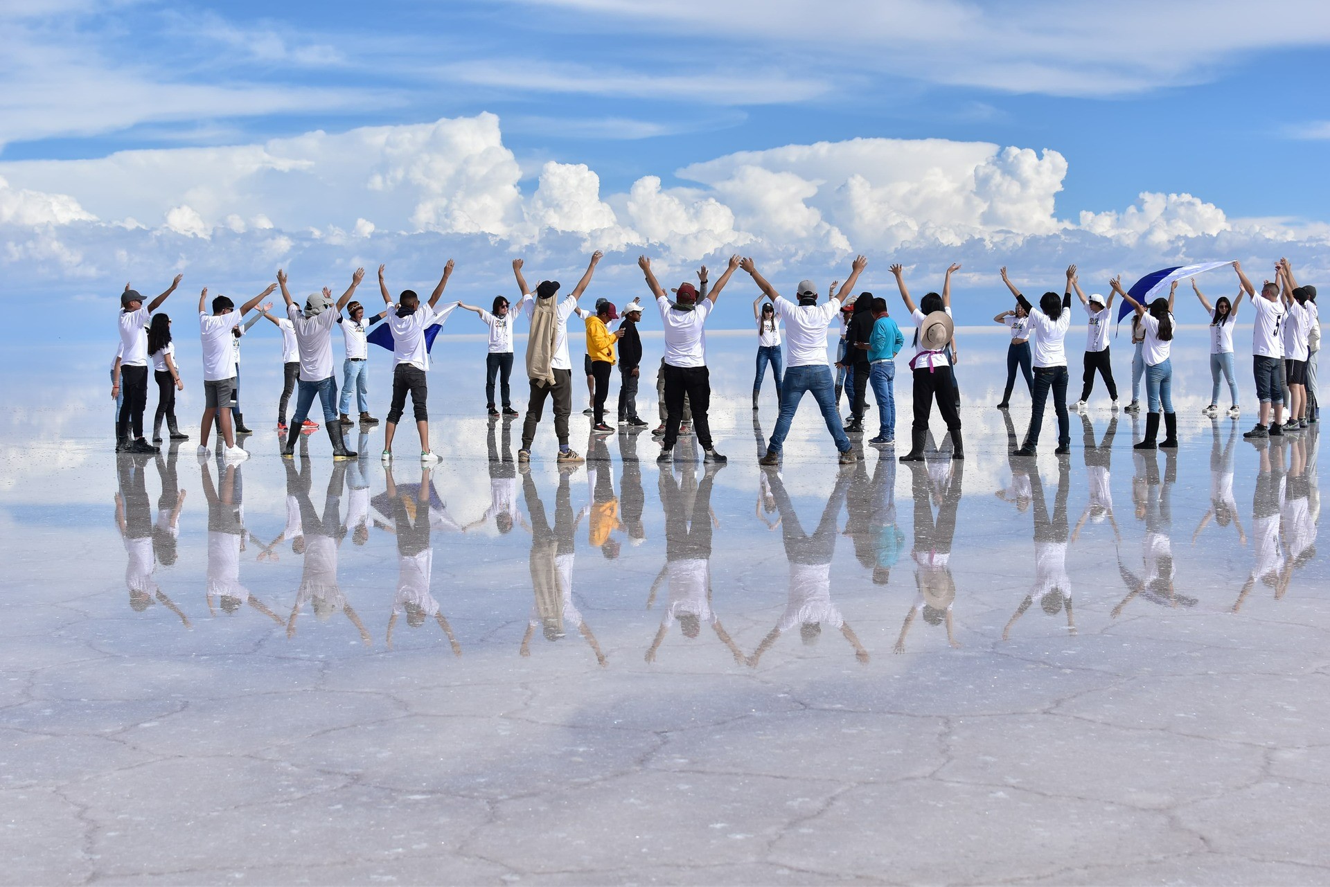 Turistas disfrutando el efecto espejo en el Salar de Uyuni durante tour de 3 días en Bolivia