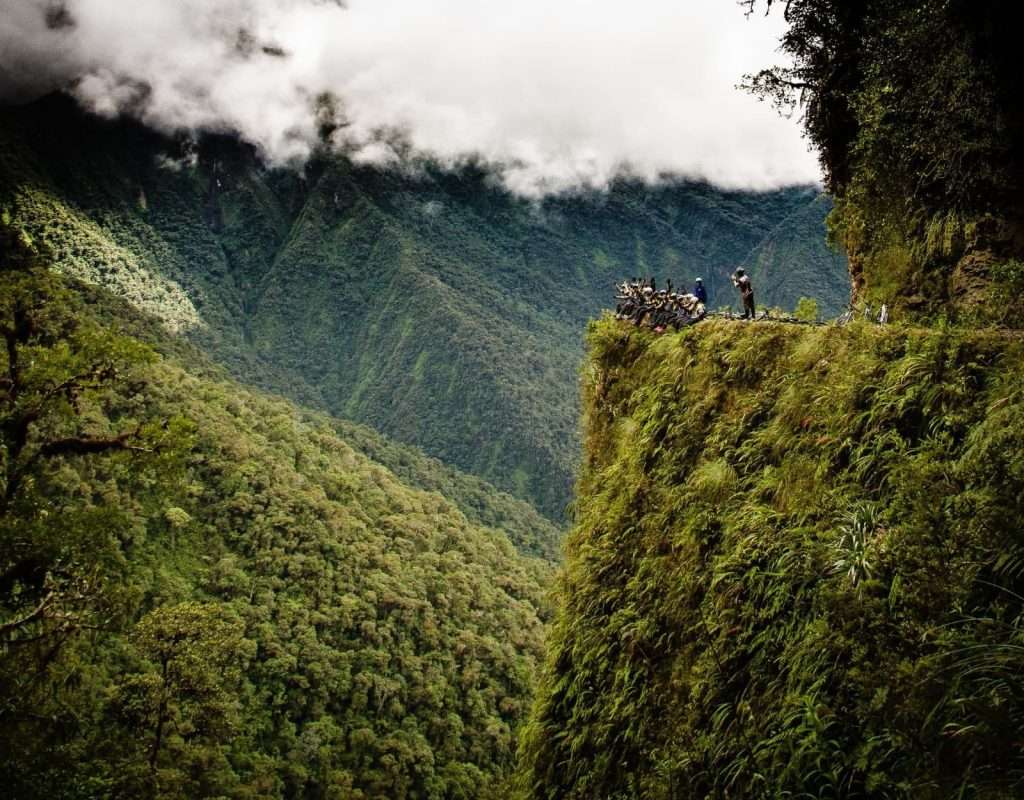 cyclists at death road bolivia cliff viewpoint overlooking yungas mountains