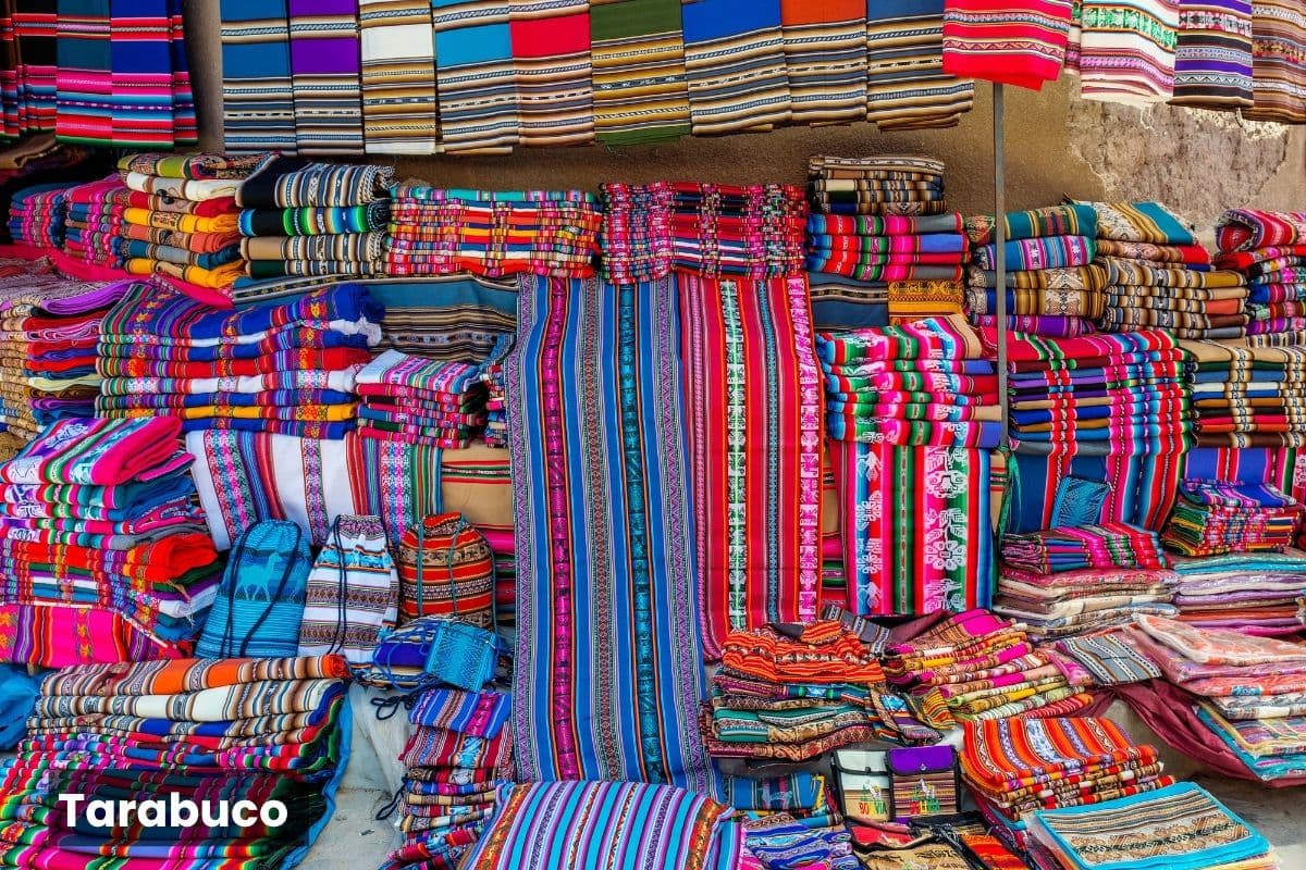 Exhibición de coloridos tejidos y textiles tradicionales en un puesto del mercado de Tarabuco, Bolivia.
