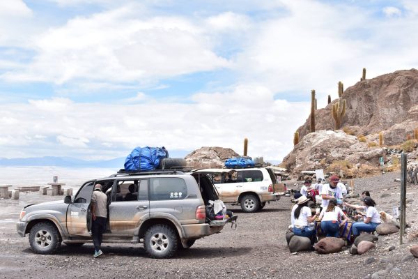Vehículo 4x4 y turistas junto a la Isla Incahuasi durante un tour de 3 días por el Salar de Uyuni.